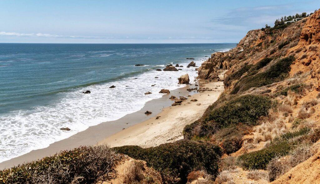 Coastal view of waves, sand, and rocky cliffs at El Matador State Beach