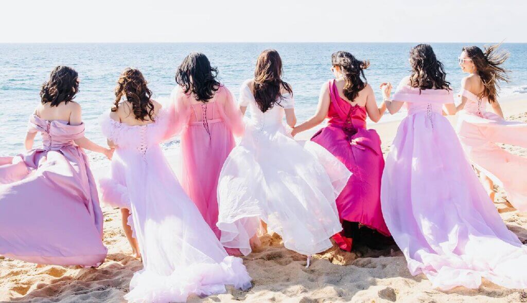Group of women in colorful dresses celebrating together along the shoreline