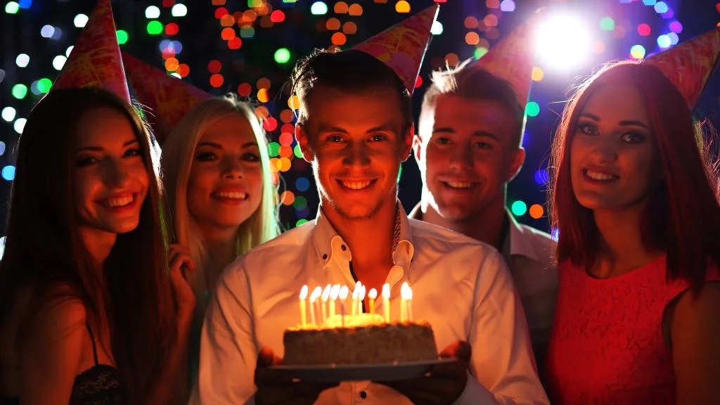 Group holding cake at night party