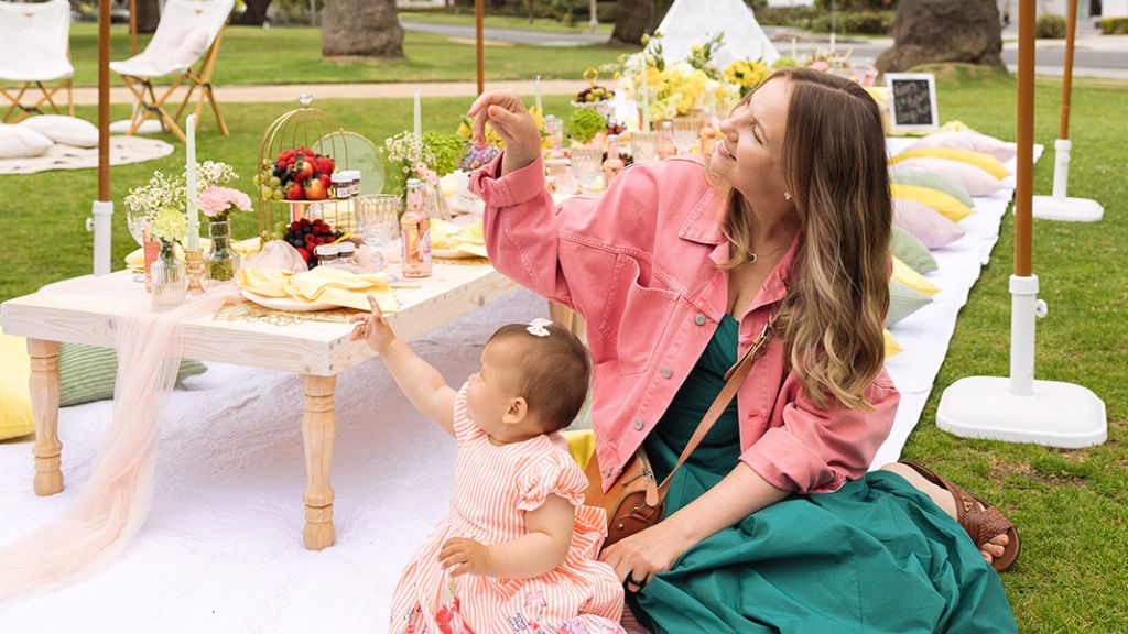 Mother and young daughter sitting beside a pink luxury picnic table