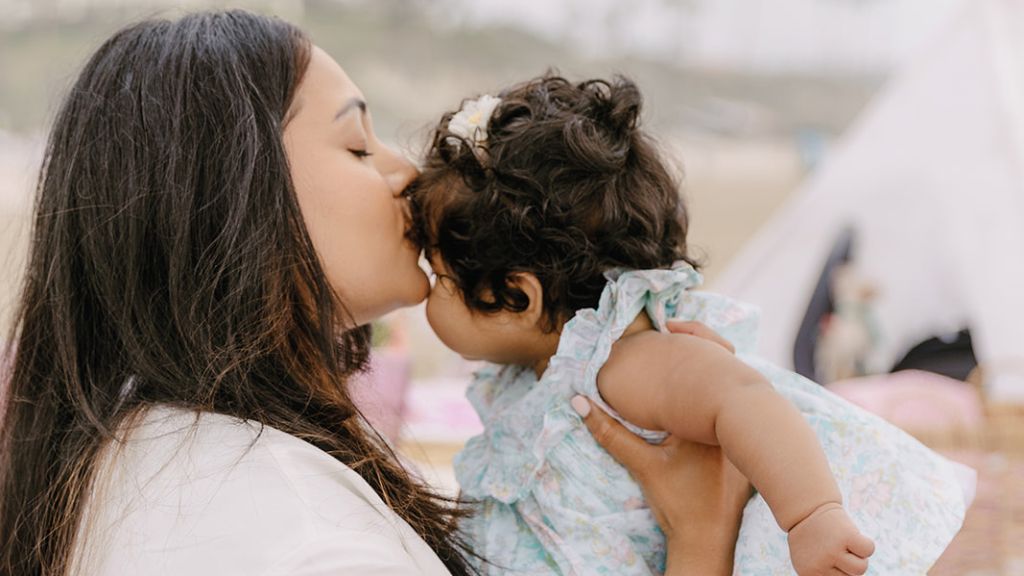 Mother kissing her young daughter during an outdoor picnic