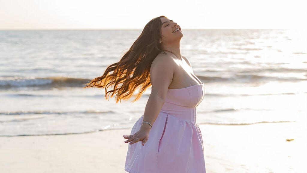 Woman in Pink Dress at the Beach at Sunset Woman in a flowing pink dress posing along the shoreline at sunset
