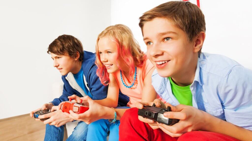 Three teenagers holding controllers and playing video games together