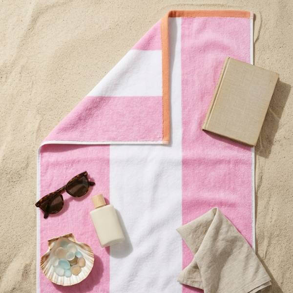 pink striped beach towel on sand