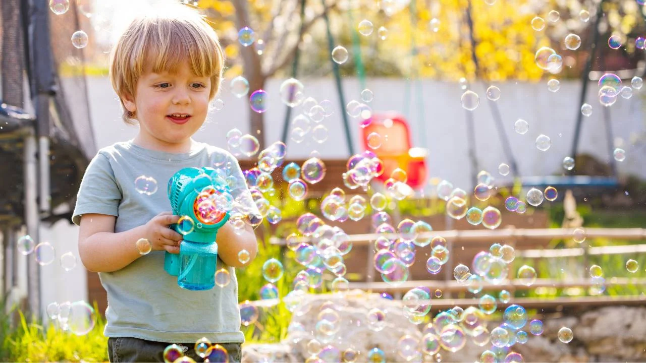 boy playing with bubble gun in backyard