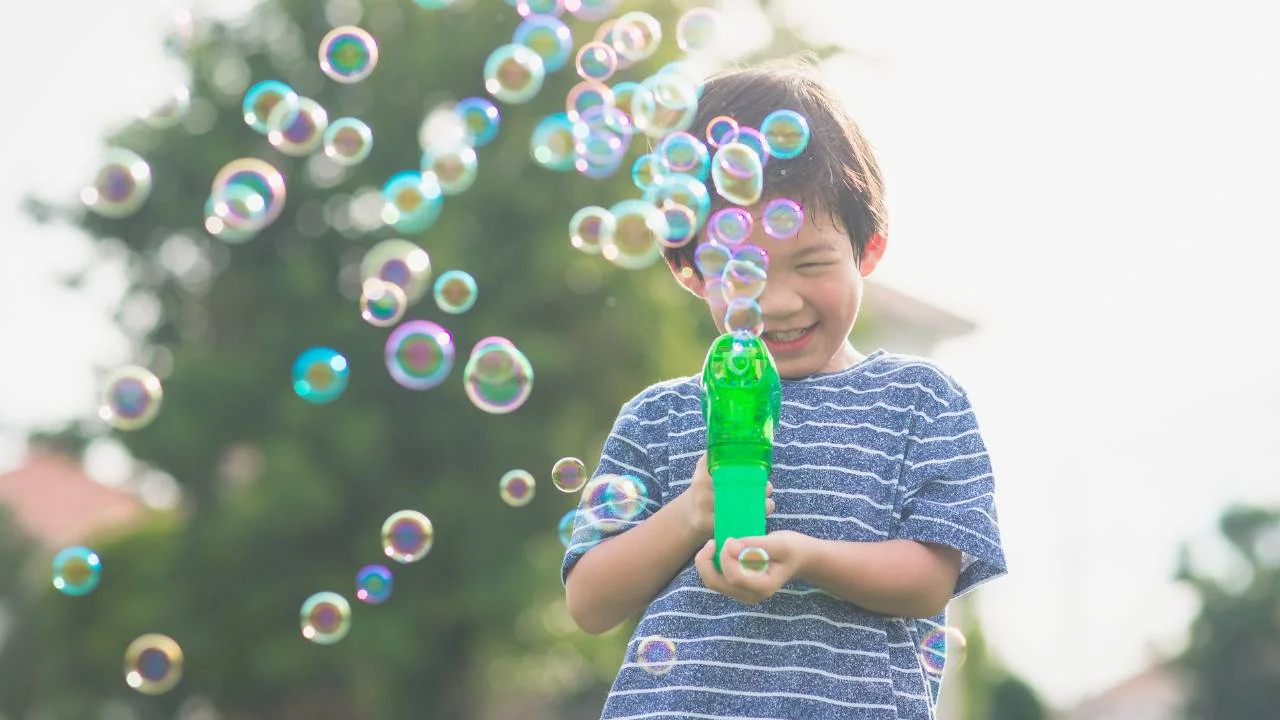 child with bubble gun outdoors