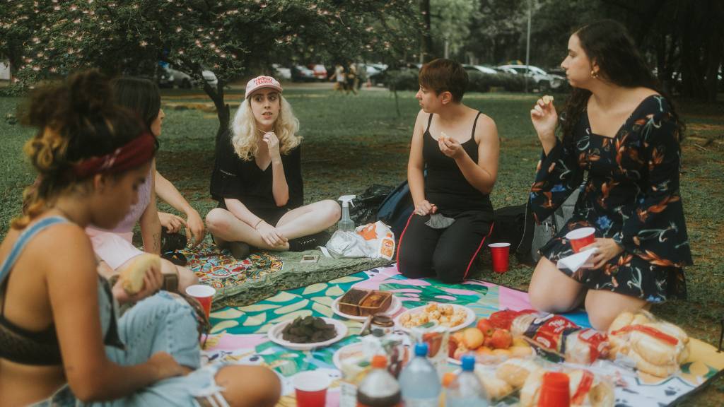 friends enjoying food on picnic blanket