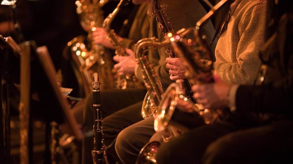 Musicians playing saxophones during a live jazz performance under warm stage lighting