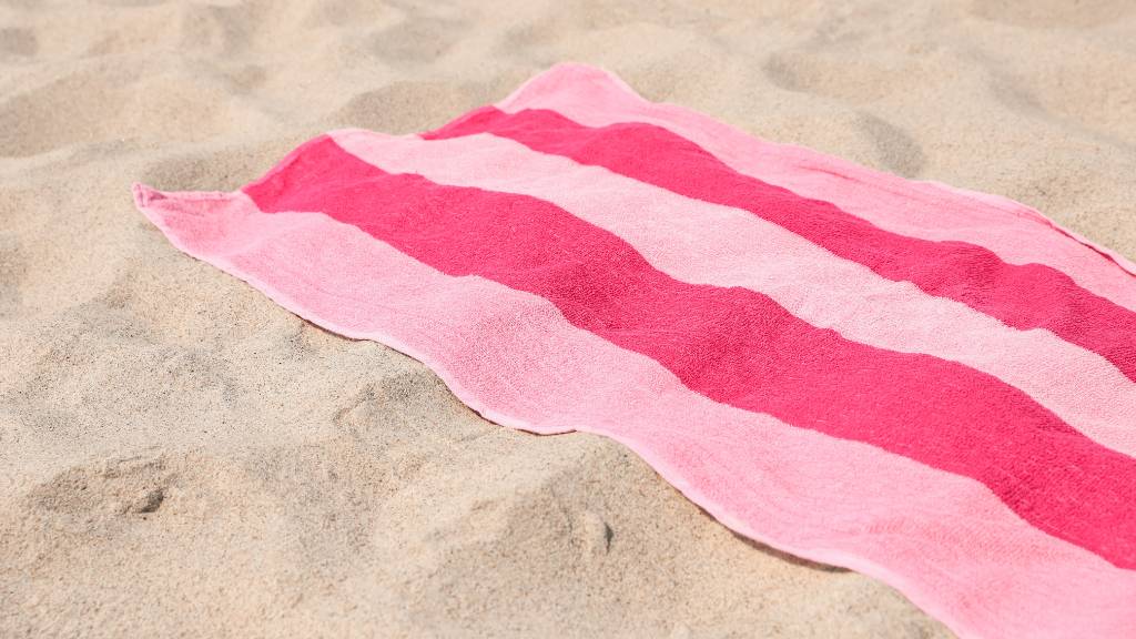 pink striped beach towel on sand