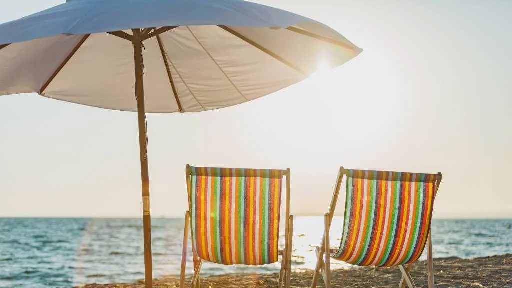striped chairs under a beach umbrella