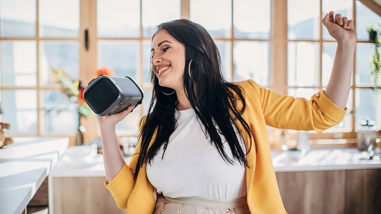 woman holding bluetooth speaker indoors