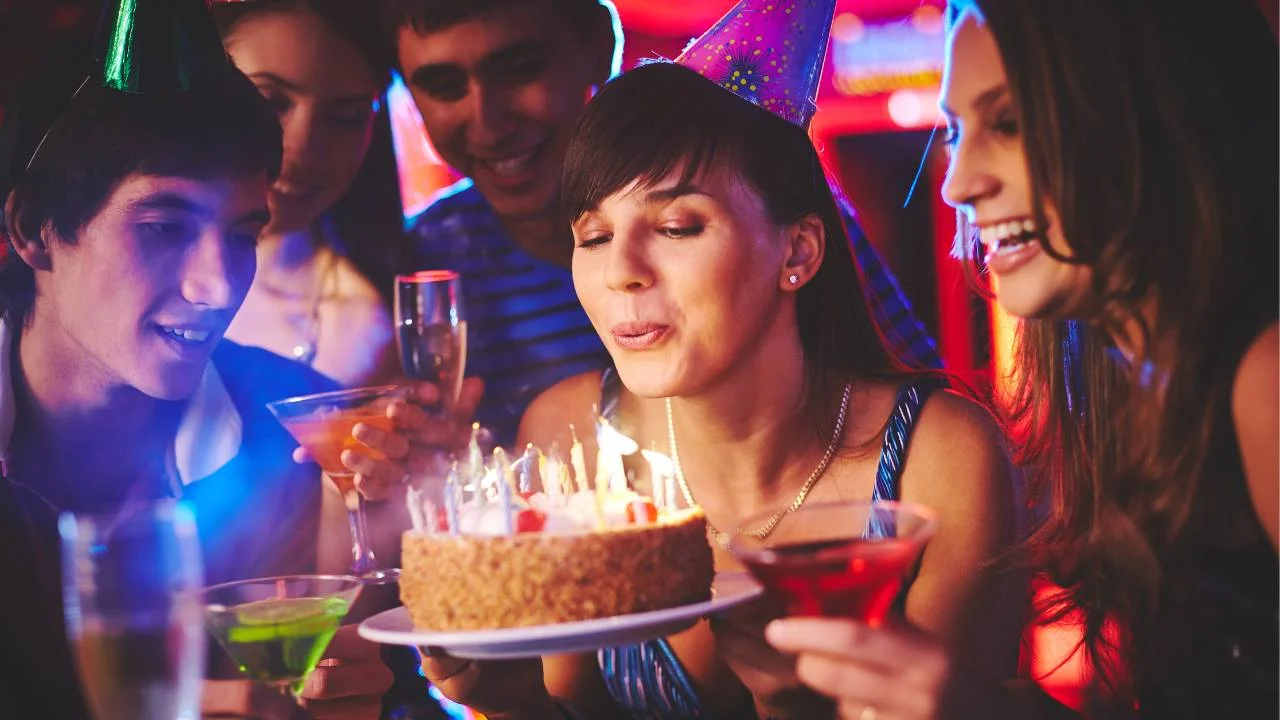 daughter-in-law blowing out birthday candles surrounded by friends