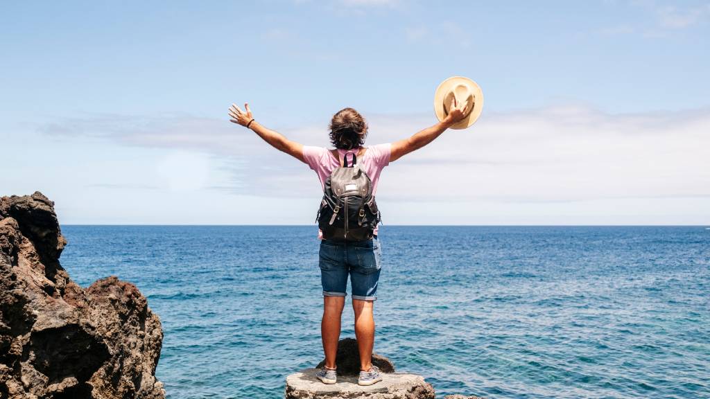 traveler wearing beach backpack by the ocean