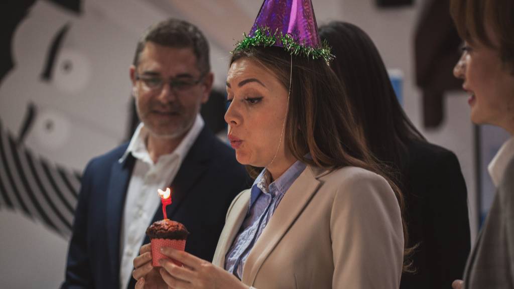 woman blowing out birthday candle on cupcake