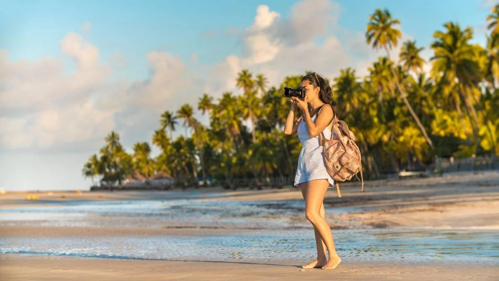 woman walking on beach with a beach bag backpack