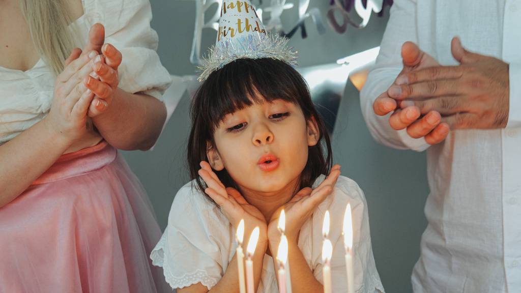 child blowing out birthday candles