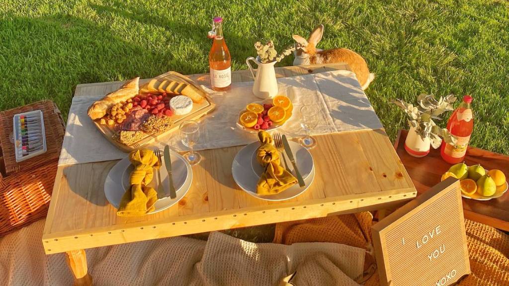 ©️ Picnic Makers - https://picnicmakers.com/ picnic table setup on grass with food and drinks