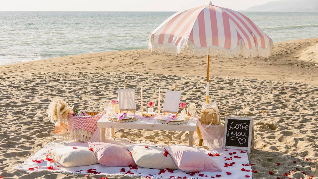 ©️ Picnic Makers - https://picnicmakers.com/  beach picnic setup with umbrella and cushions