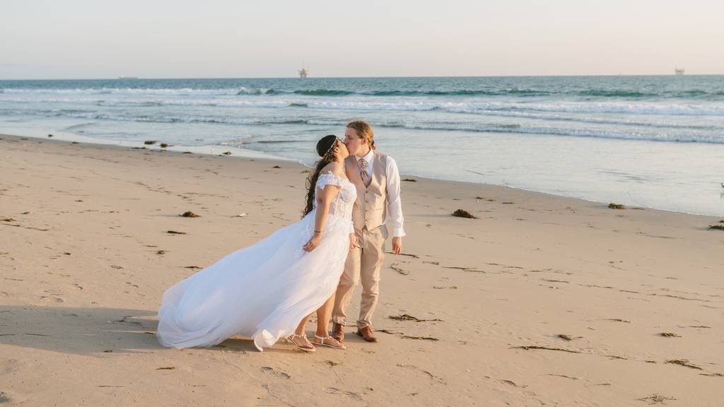 Bride and groom walking on the beach after their wedding ceremony.