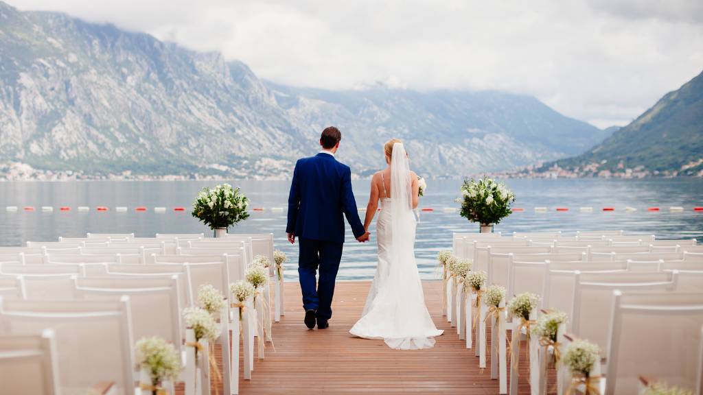 Couple walking down the aisle at an outdoor wedding ceremony with mountain views.