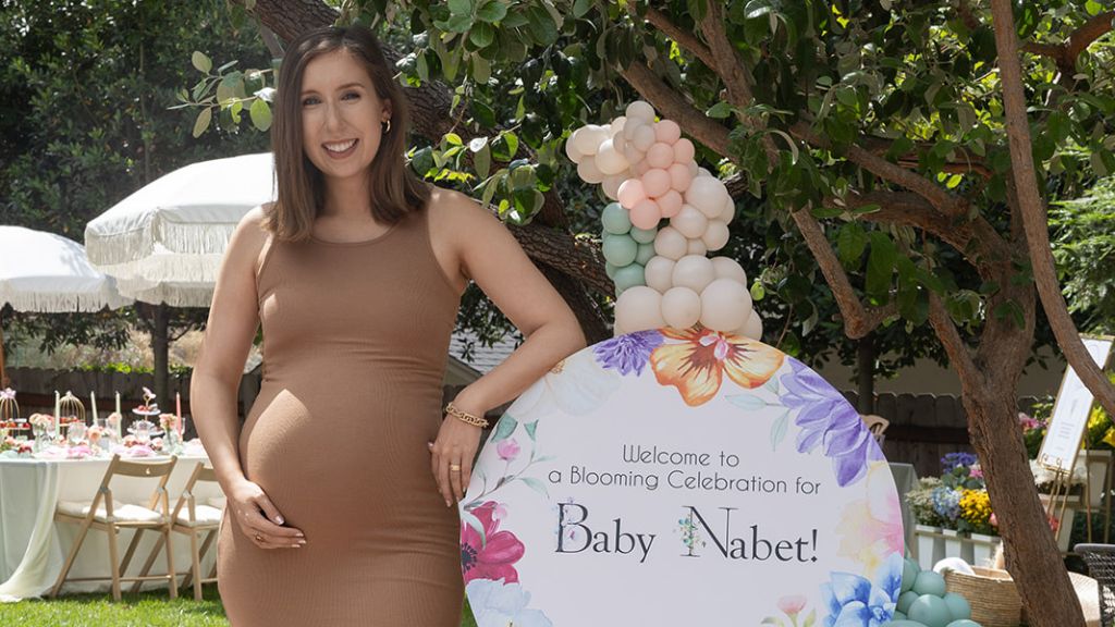 expecting mother standing beside baby welcome sign