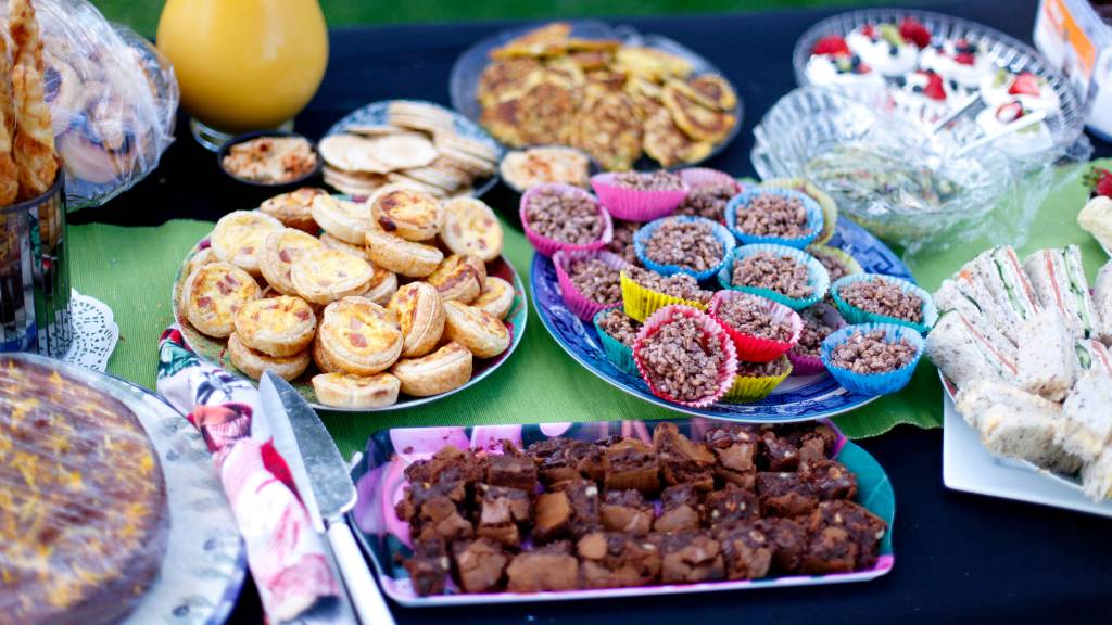 Variety of colorful homemade picnic snacks, pastries, and skewers on outdoor table