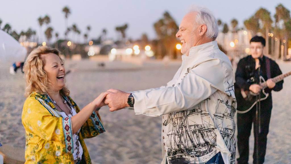 joyful married couple dancing at beach