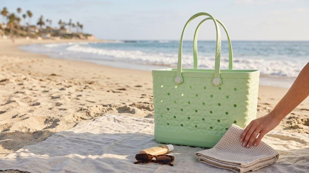 Light green LiAYiD textured beach tote on a blanket beside sunglasses and folded towels