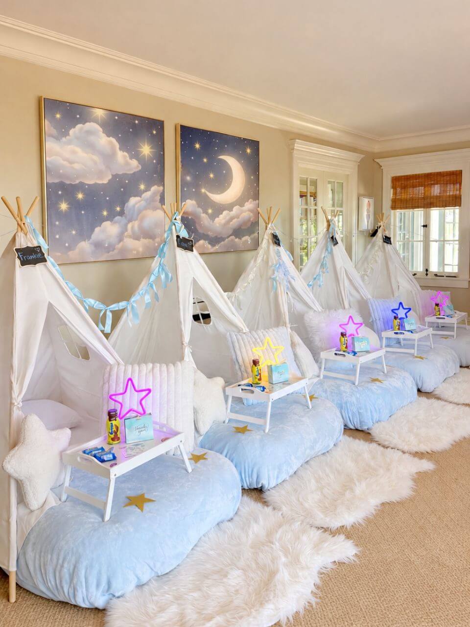 Blue moon and stars sleepover party setup with white teepees, light blue bedding and star lights